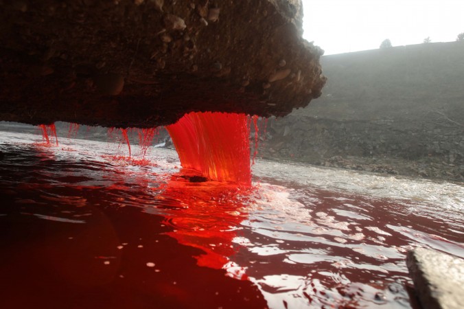 Agua y el suelo que se han teñido de rojo tras ser contaminados por deshechos industriales de una fábrica de tinte ya cerrada, en medio de fuertes lluvias en una montaña en Ruyang, en la provincia de Henan. Según el gobierno local, la fábrica estaba operando sin las licencias necesarias y fue clausurada por las autoridades el pasado año tras una explosión que causó una fuga de tinte y contaminó el agua subterránea.