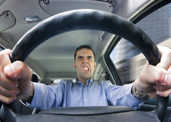 A furious man driving, as seen from behind the wheel. Shot using a very wide fisheye lens.